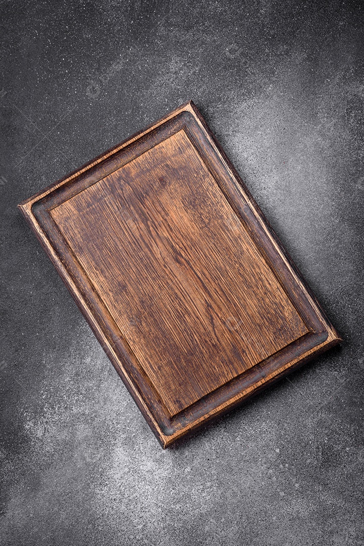 Tábua de corte de madeira vazia sobre um fundo de textura leve. Utensílios de cozinha