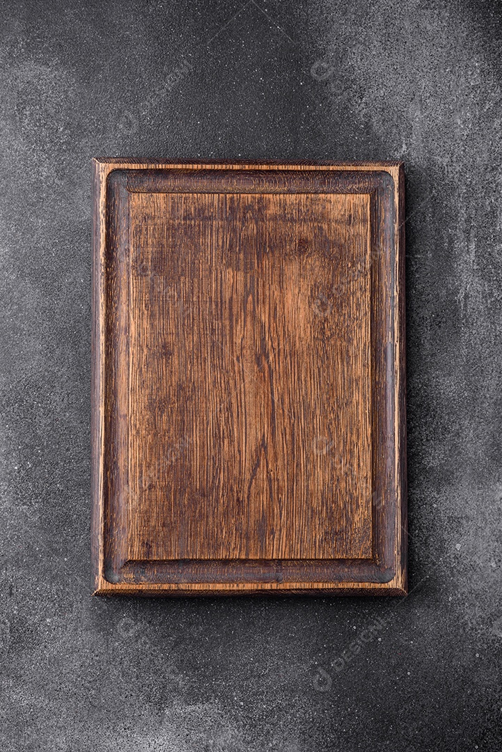 Tábua de corte de madeira vazia sobre um fundo de textura leve. Utensílios de cozinha