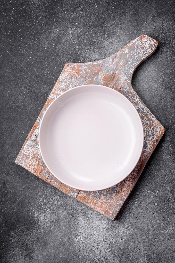 Placa cerâmica redonda vazia sobre um fundo de textura leve. Utensílios de cozinha