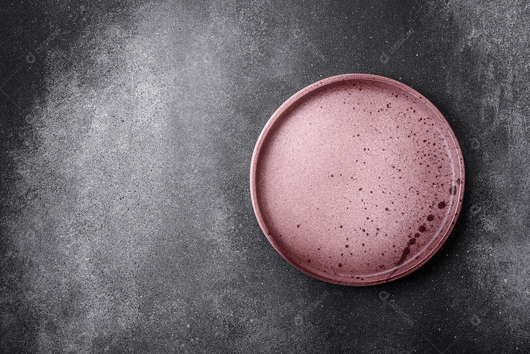 Placa cerâmica redonda vazia sobre um fundo de textura leve. Utensílios de cozinha