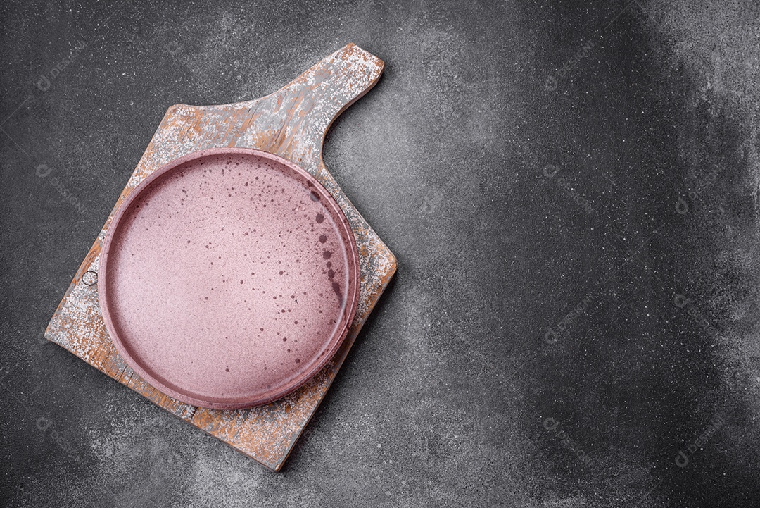 Placa cerâmica redonda vazia sobre um fundo de textura leve. Utensílios de cozinha