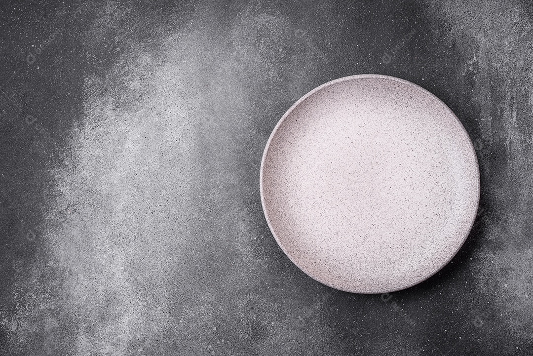 Placa cerâmica redonda vazia sobre um fundo de textura leve. Utensílios de cozinha