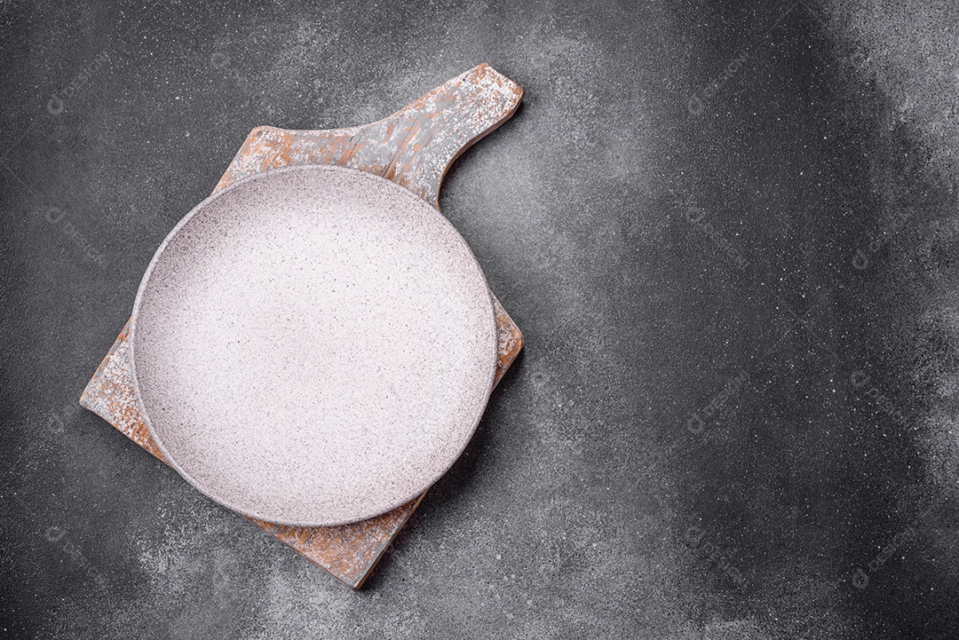 Placa cerâmica redonda vazia sobre um fundo de textura leve. Utensílios de cozinha