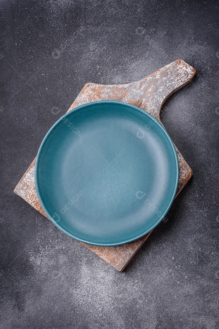 Placa cerâmica redonda vazia sobre um fundo de textura leve. Utensílios de cozinha