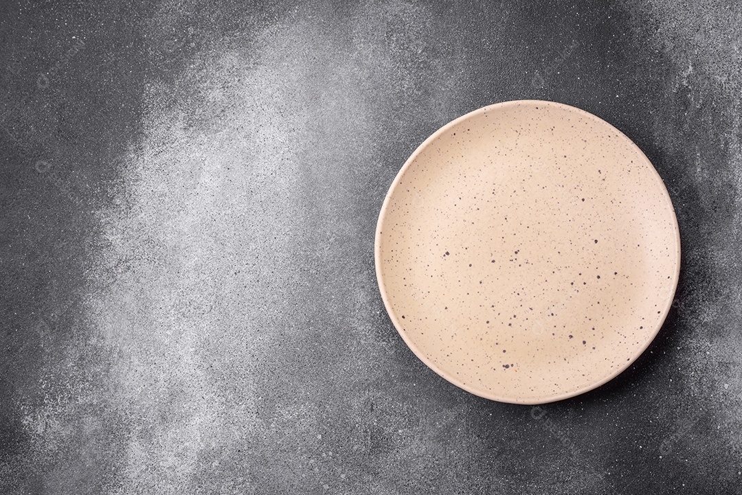 Placa cerâmica redonda vazia sobre um fundo de textura leve. Utensílios de cozinha