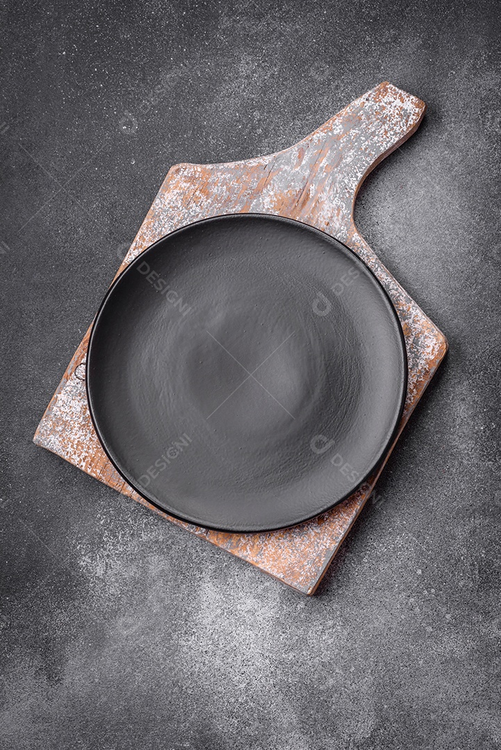 Placa cerâmica redonda vazia sobre um fundo de textura leve. Utensílios de cozinha