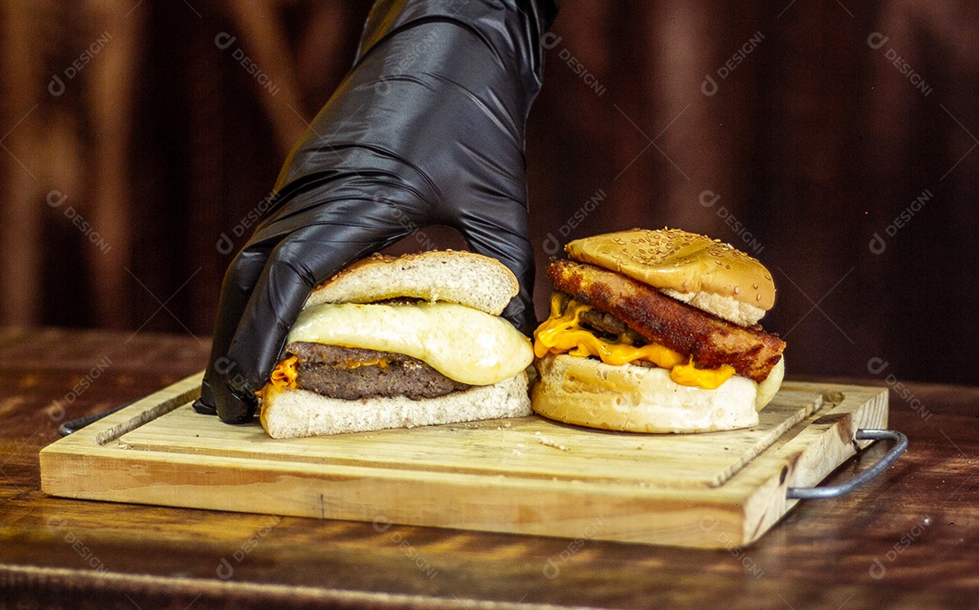 Tábua de madeira com dois hamburgue com muito queijo e bacon