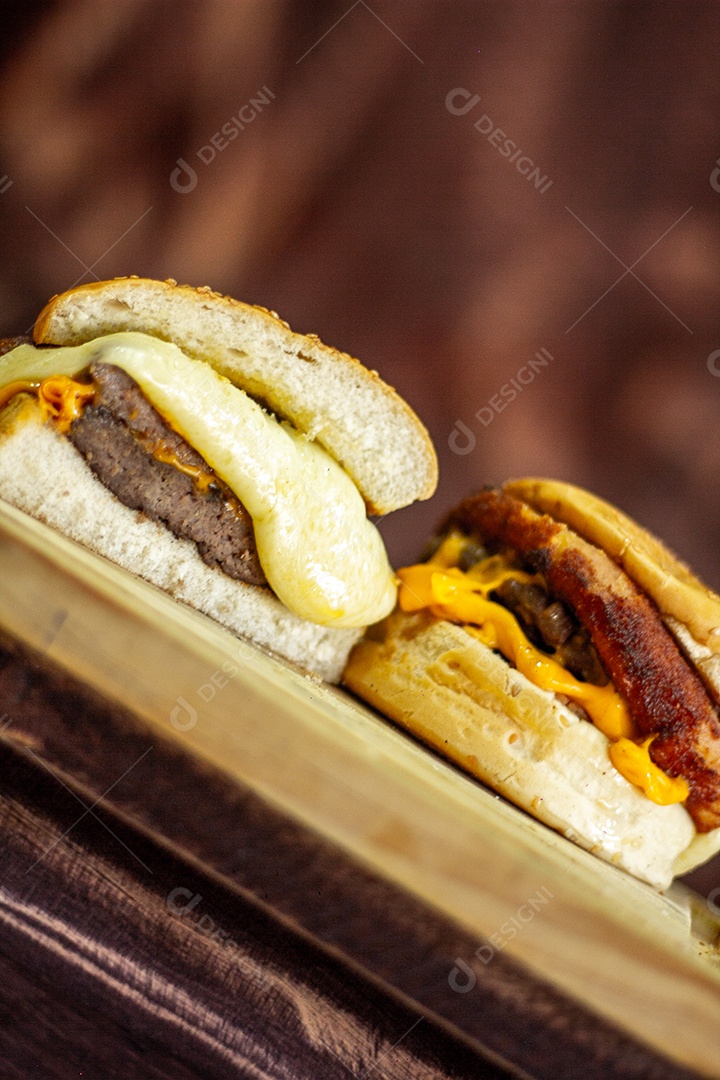 Dois hamburgueres deliciosos sobre unma tábua de madeira