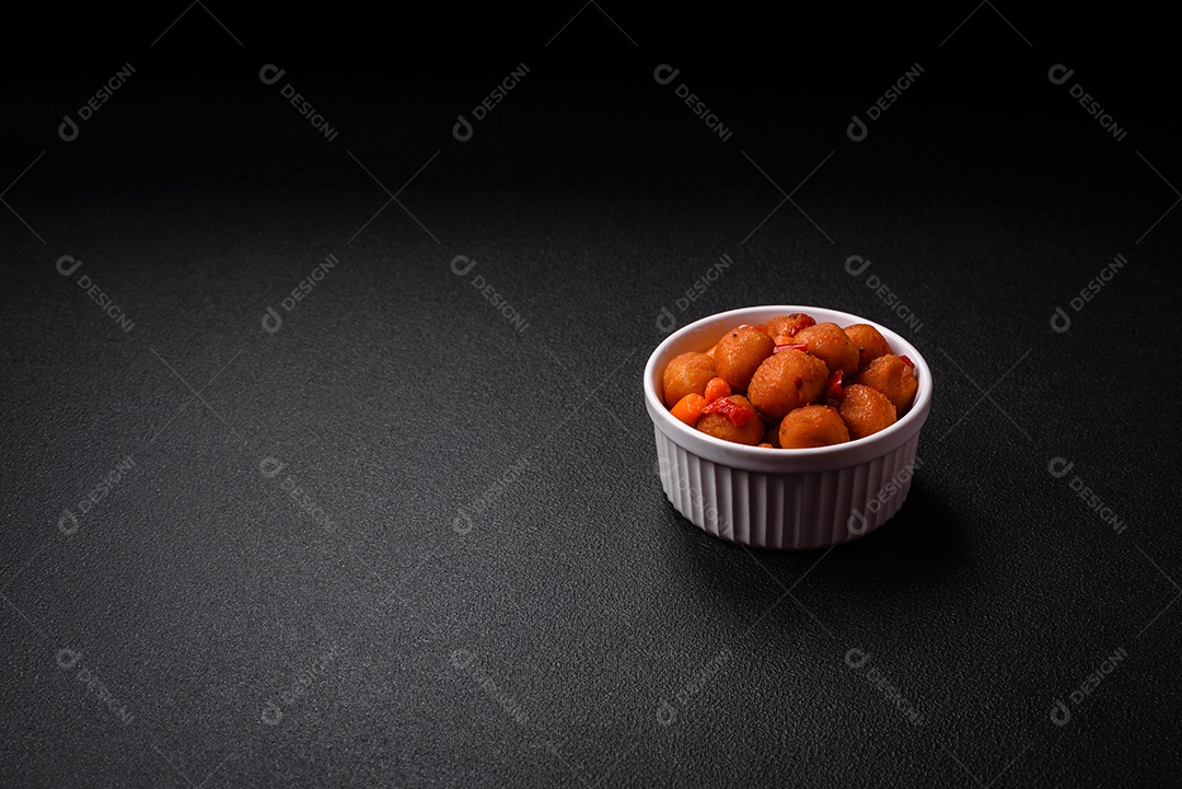 Deliciosas bolas de batata frita com legumes, sal, especiarias e ervas sobre um fundo escuro de concreto