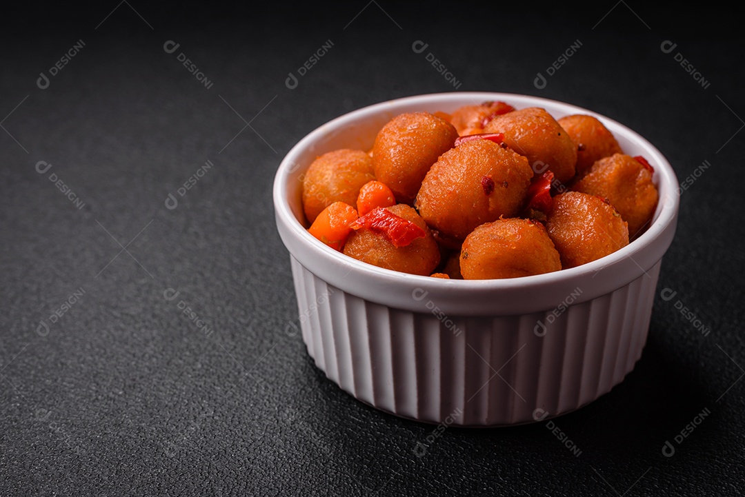 Deliciosas bolas de batata frita com legumes, sal, especiarias e ervas sobre um fundo escuro de concreto