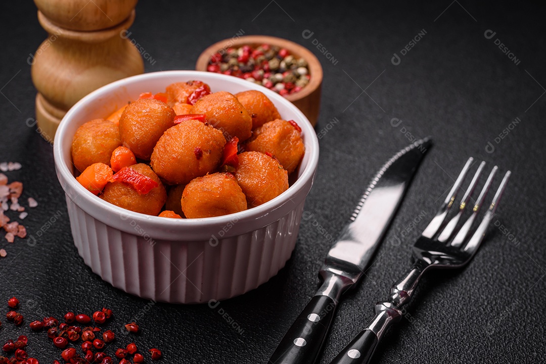 Deliciosas bolas de batata frita com legumes, sal, especiarias e ervas sobre um fundo escuro de concreto