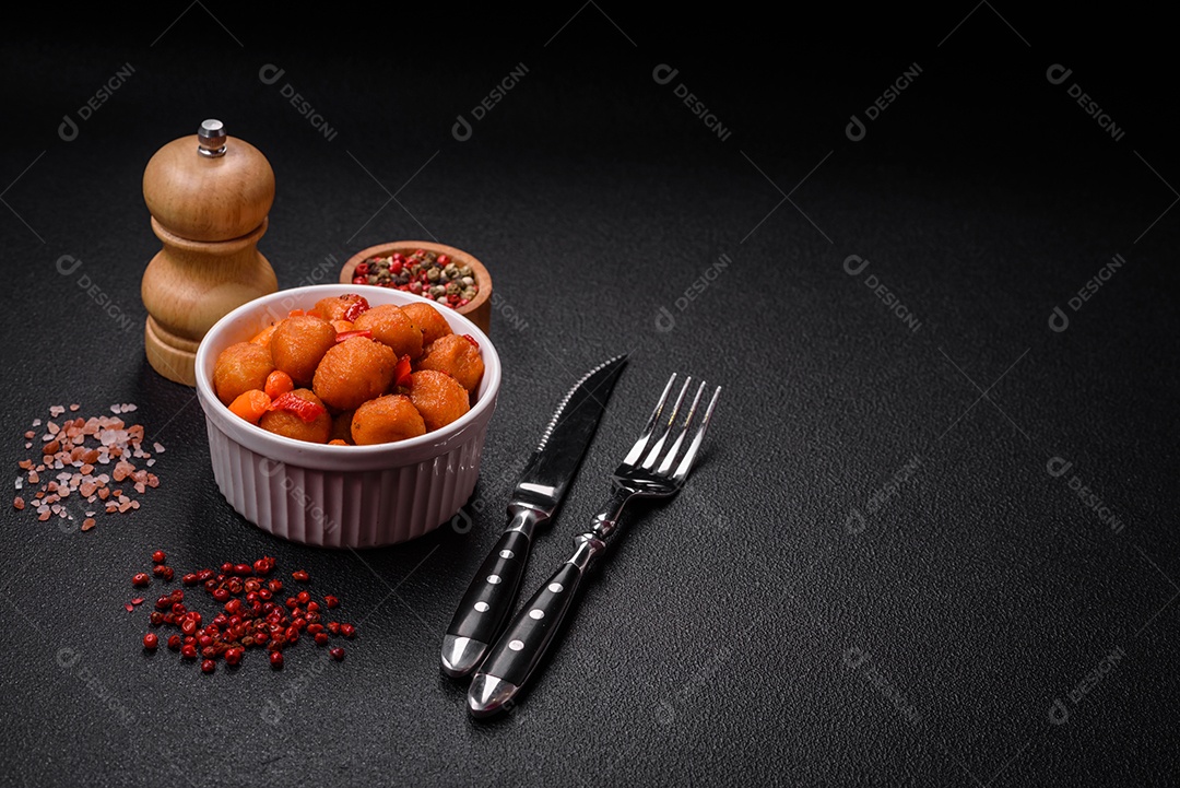 Deliciosas bolas de batata frita com legumes, sal, especiarias e ervas sobre um fundo escuro de concreto