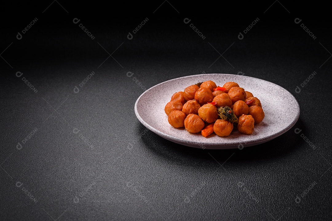 Deliciosas bolas de batata frita com legumes, sal, especiarias e ervas sobre um fundo escuro de concreto