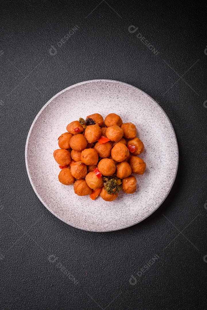 Deliciosas bolas de batata frita com legumes, sal, especiarias e ervas sobre um fundo escuro de concreto
