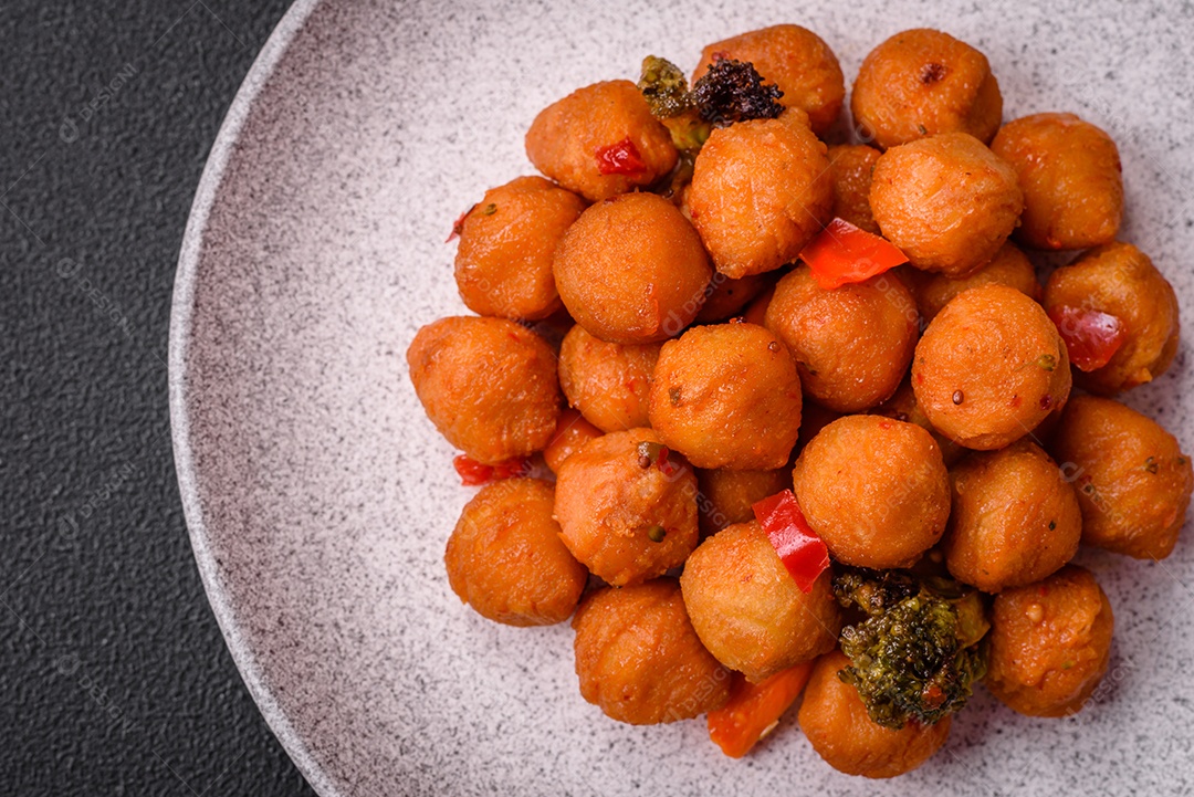 Deliciosas bolas de batata frita com legumes, sal, especiarias e ervas sobre um fundo escuro de concreto