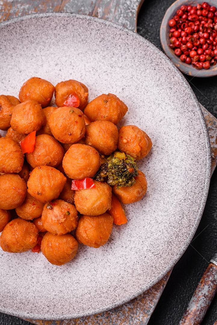Deliciosas bolas de batata frita com legumes, sal, especiarias e ervas sobre um fundo escuro de concreto