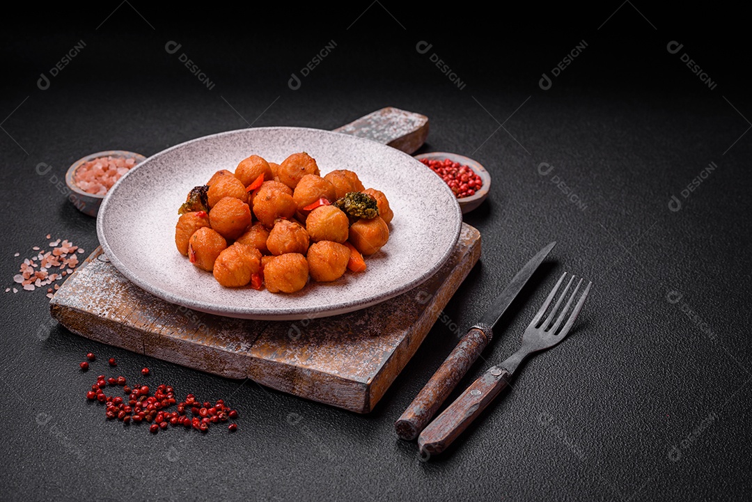 Deliciosas bolas de batata frita com legumes, sal, especiarias e ervas sobre um fundo escuro de concreto