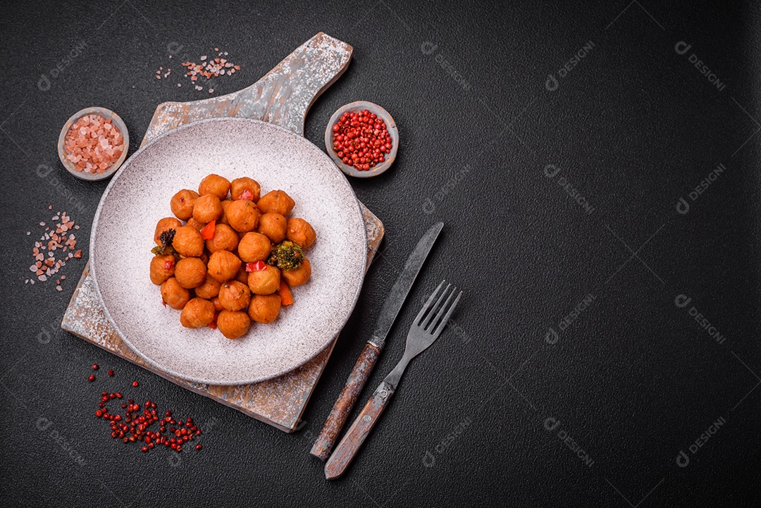 Deliciosas bolas de batata frita com legumes, sal, especiarias e ervas sobre um fundo escuro de concreto