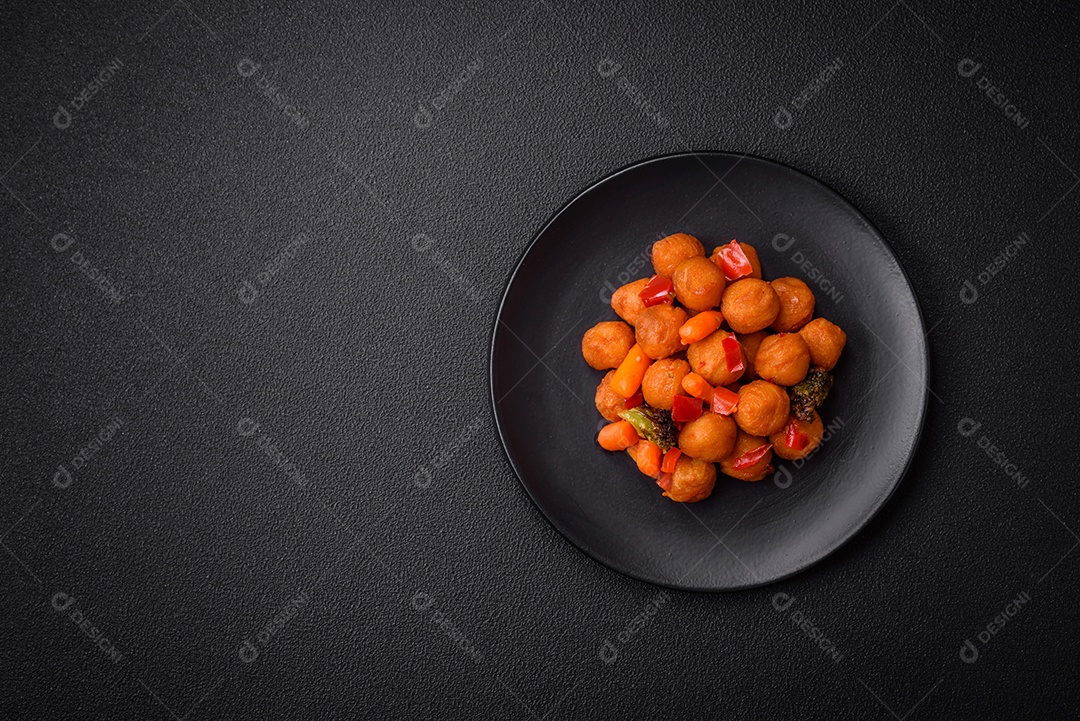 Deliciosas bolas de batata frita com legumes, sal, especiarias e ervas sobre um fundo escuro de concreto