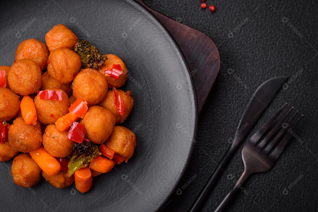 Deliciosas bolas de batata frita com legumes, sal, especiarias e ervas sobre um fundo escuro de concreto
