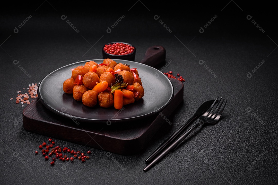 Deliciosas bolas de batata frita com legumes, sal, especiarias e ervas sobre um fundo escuro de concreto