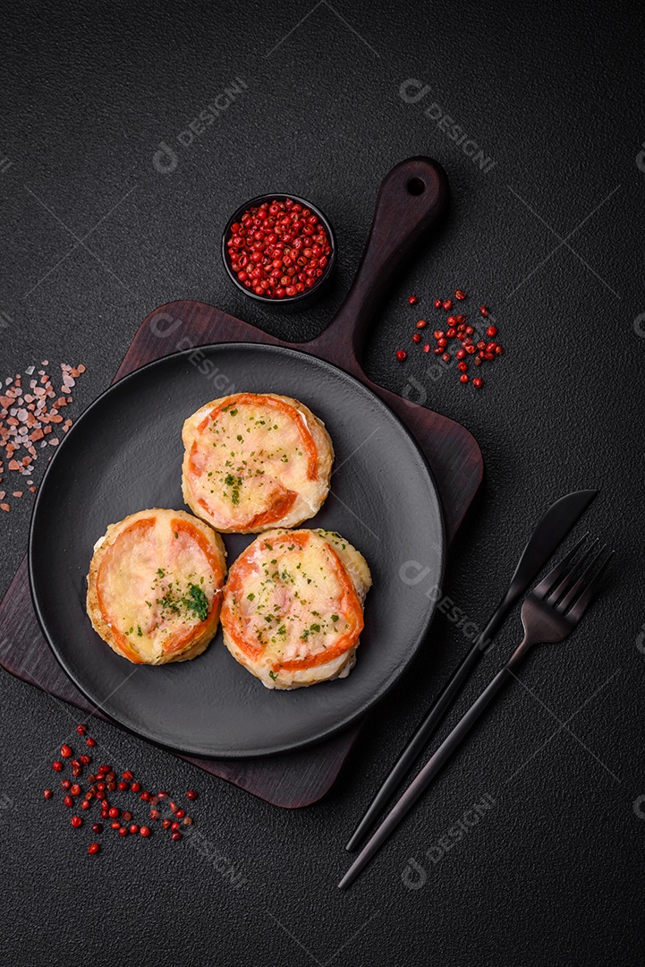 Delicioso filé de peixe assado com queijo, tomate, sal, especiarias e ervas sobre um fundo escuro de concreto