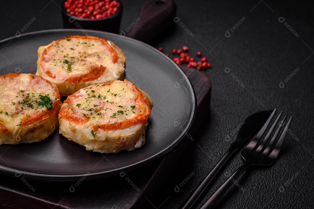 Delicioso filé de peixe assado com queijo, tomate, sal, especiarias e ervas sobre um fundo escuro de concreto