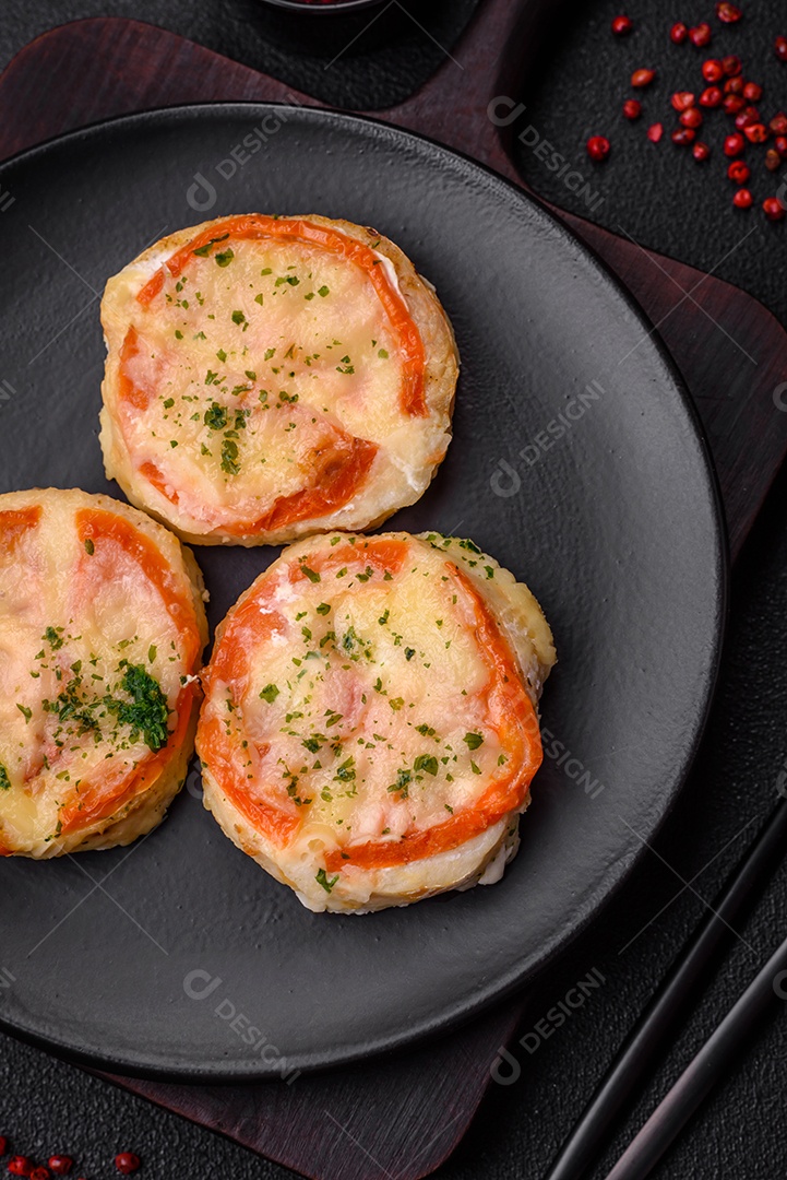 Delicioso filé de peixe assado com queijo, tomate, sal, especiarias e ervas sobre um fundo escuro de concreto