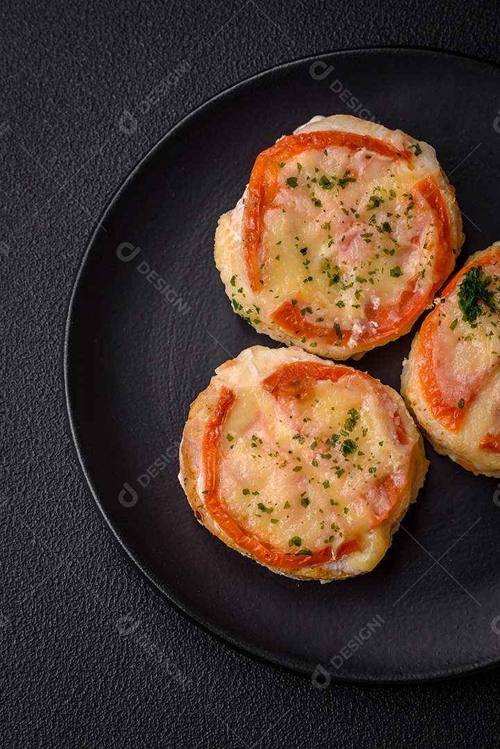 Delicioso filé de peixe assado com queijo, tomate, sal, especiarias e ervas sobre um fundo escuro de concreto