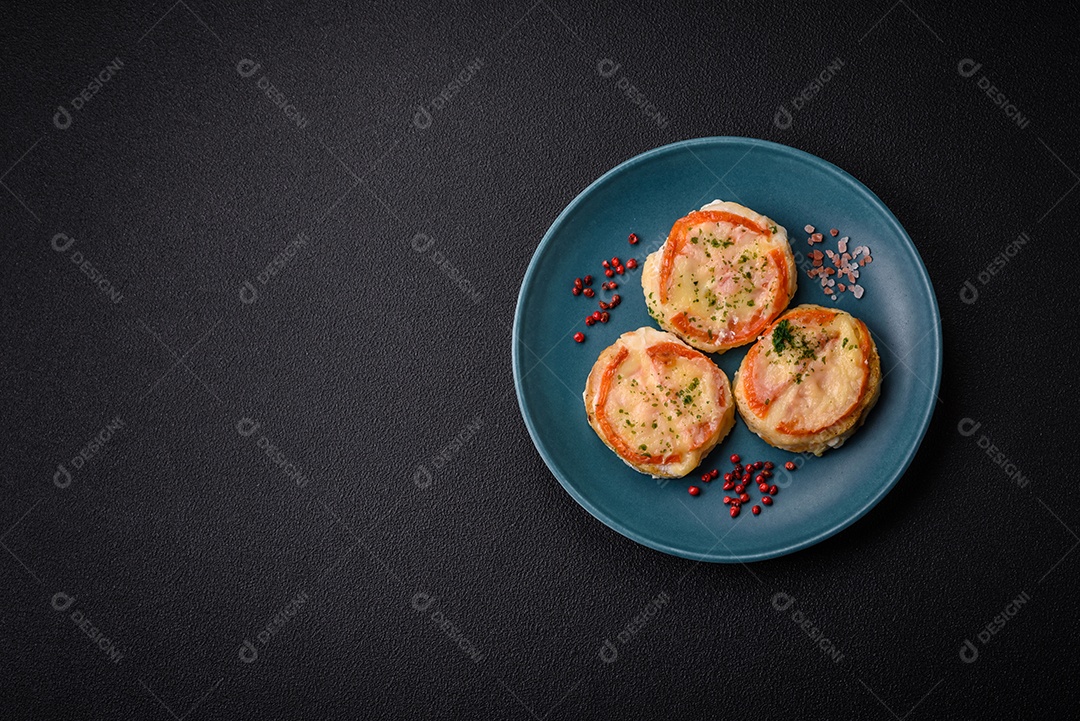 Delicioso filé de peixe assado com queijo, tomate, sal, especiarias e ervas sobre um fundo escuro de concreto