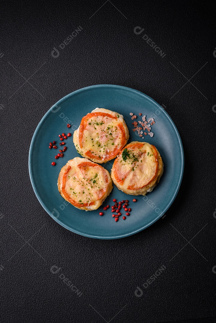 Delicioso filé de peixe assado com queijo, tomate, sal, especiarias e ervas sobre um fundo escuro de concreto