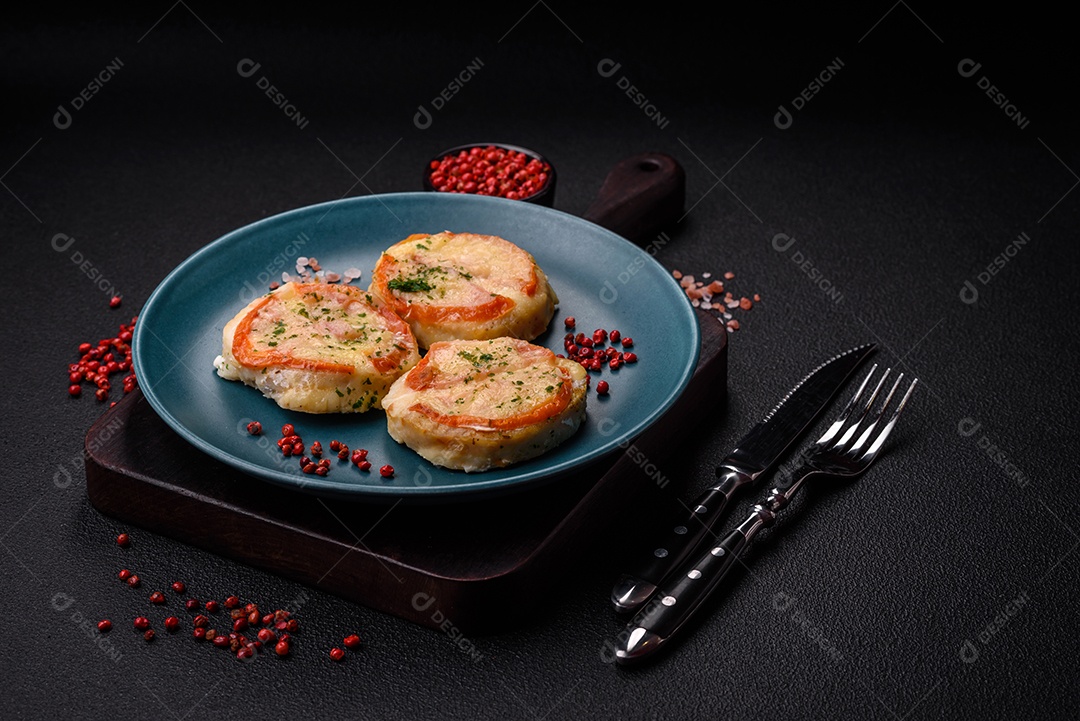 Delicioso filé de peixe assado com queijo, tomate, sal, especiarias e ervas sobre um fundo escuro de concreto