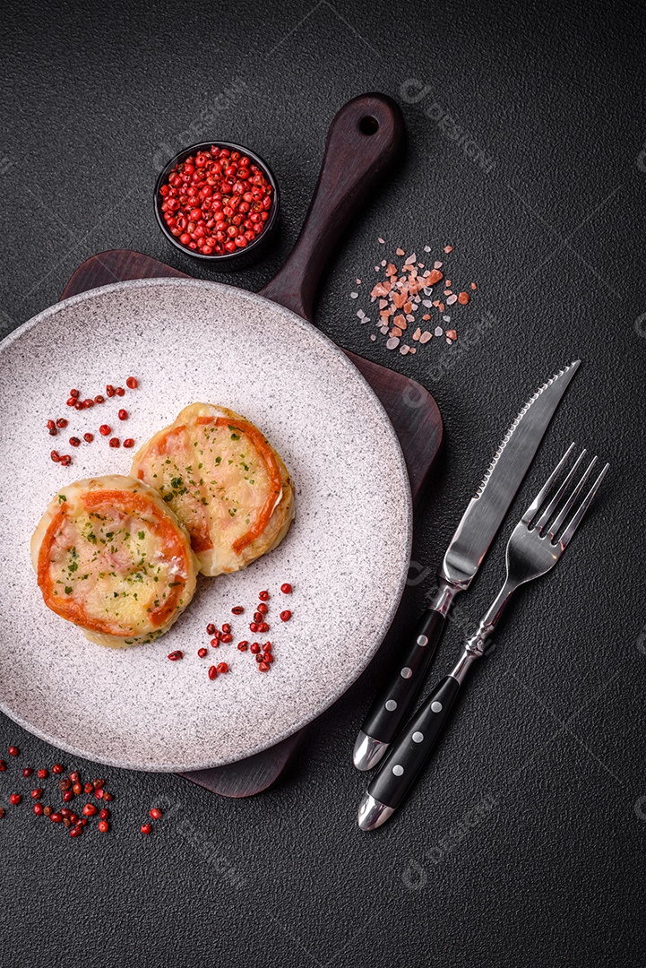 Delicioso filé de peixe assado com queijo, tomate, sal, especiarias e ervas sobre um fundo escuro de concreto