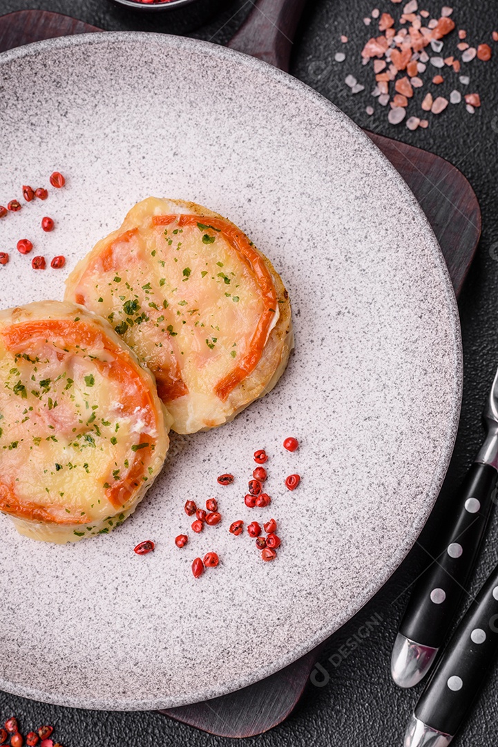 Delicioso filé de peixe assado com queijo, tomate, sal, especiarias e ervas sobre um fundo escuro de concreto
