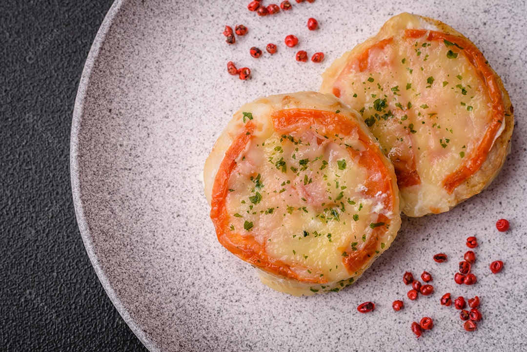 Delicioso filé de peixe assado com queijo, tomate, sal, especiarias e ervas sobre um fundo escuro de concreto