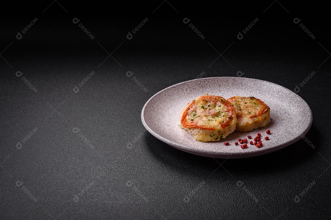 Delicioso filé de peixe assado com queijo, tomate, sal, especiarias e ervas sobre um fundo escuro de concreto