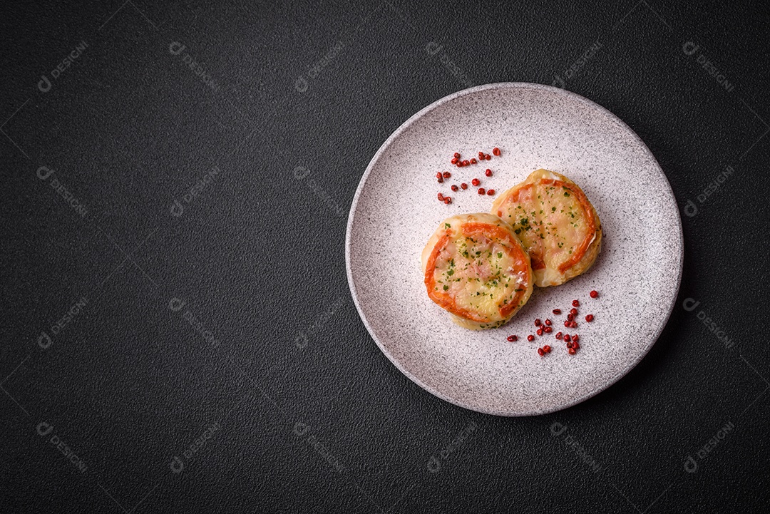 Delicioso filé de peixe assado com queijo, tomate, sal, especiarias e ervas sobre um fundo escuro de concreto