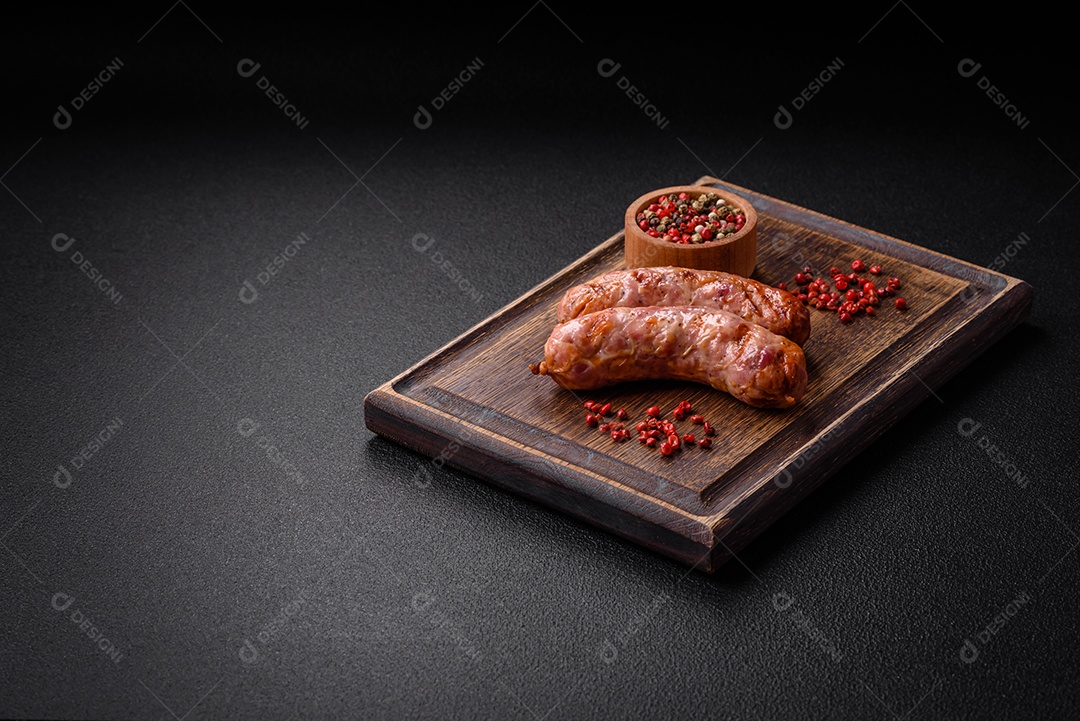 Deliciosas salsichas grelhadas de frango ou porco com sal e especiarias sobre um fundo escuro de concreto