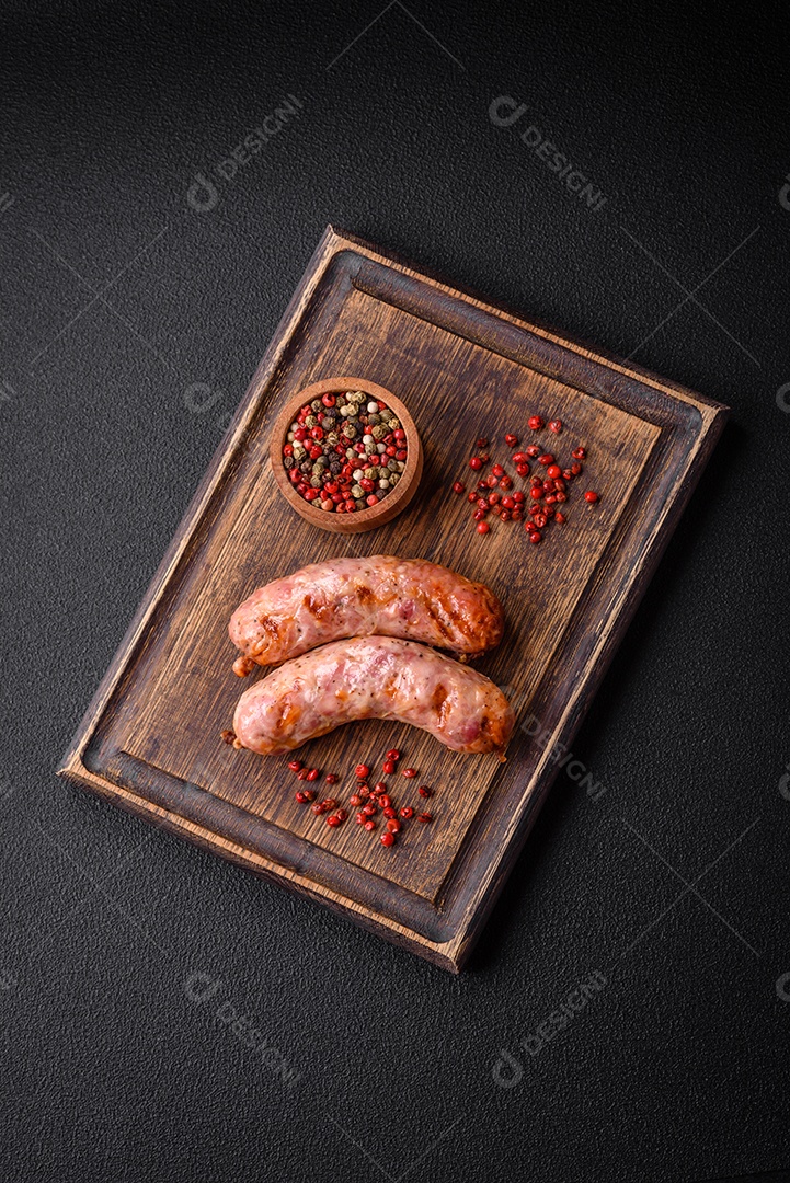Deliciosas salsichas grelhadas de frango ou porco com sal e especiarias sobre um fundo escuro de concreto