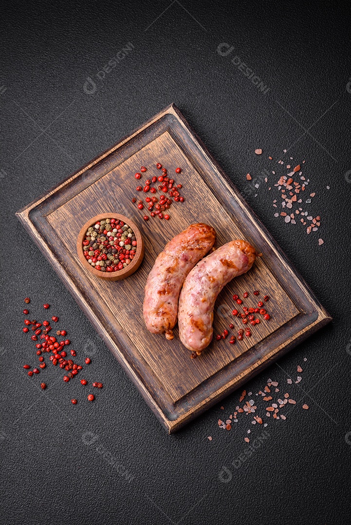 Deliciosas salsichas grelhadas de frango ou porco com sal e especiarias sobre um fundo escuro de concreto