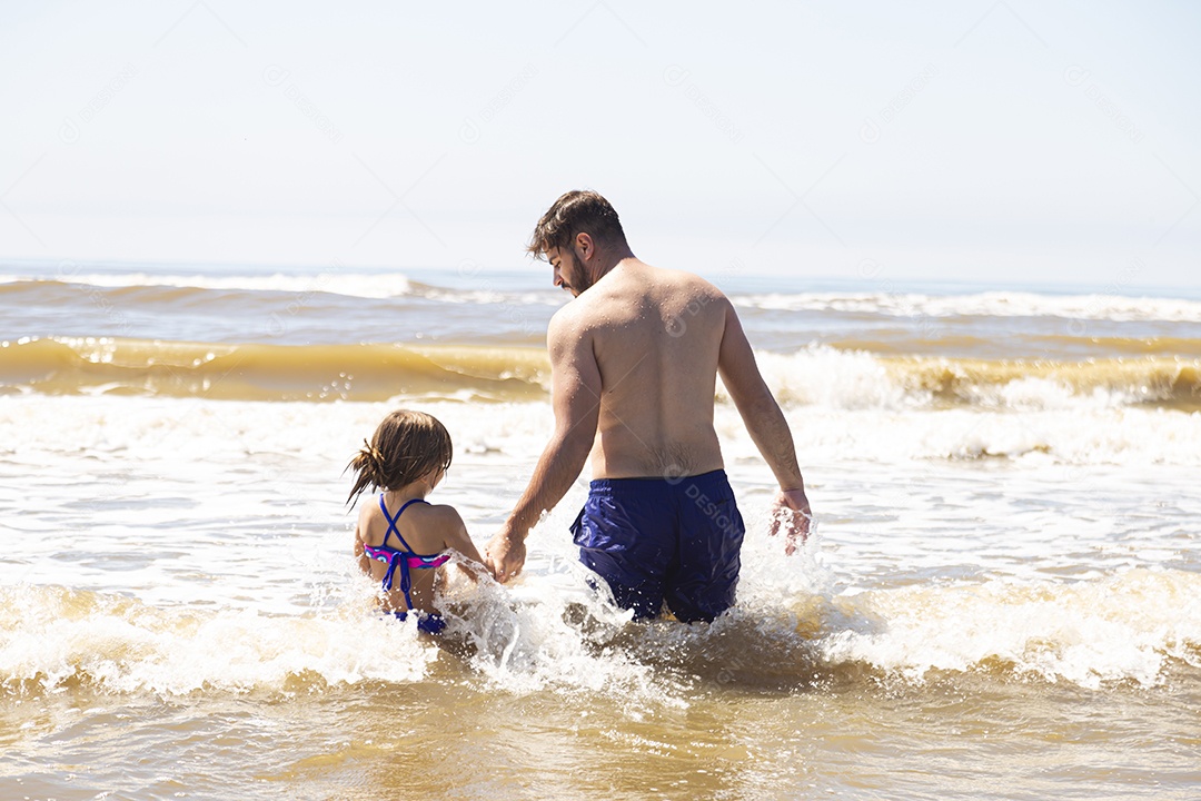 Pai ao lado de sua filha curtindo verão sobre uma praia