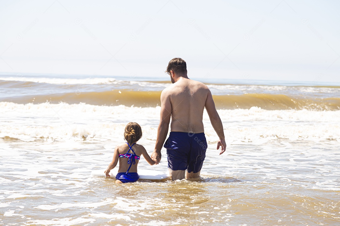 Pai ao lado de sua filha curtindo verão sobre uma praia