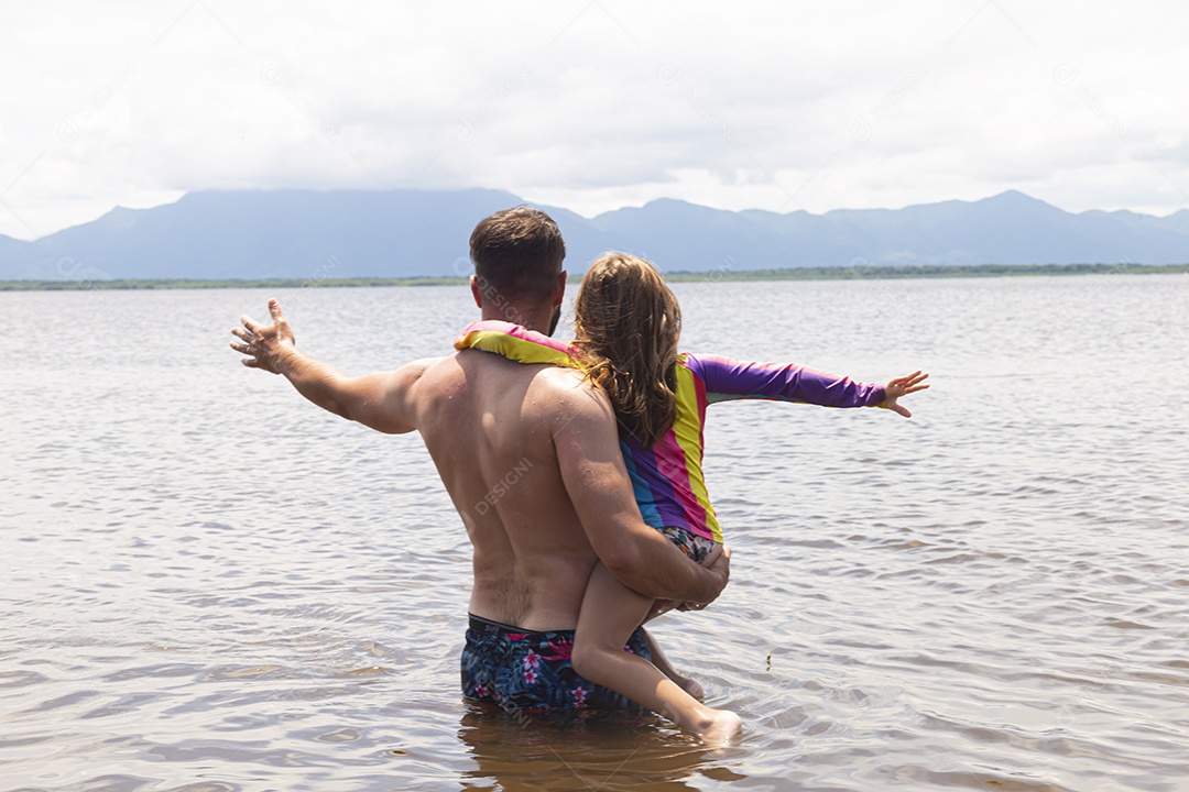 Pai ao lado de sua filha curtindo verão sobre uma praia