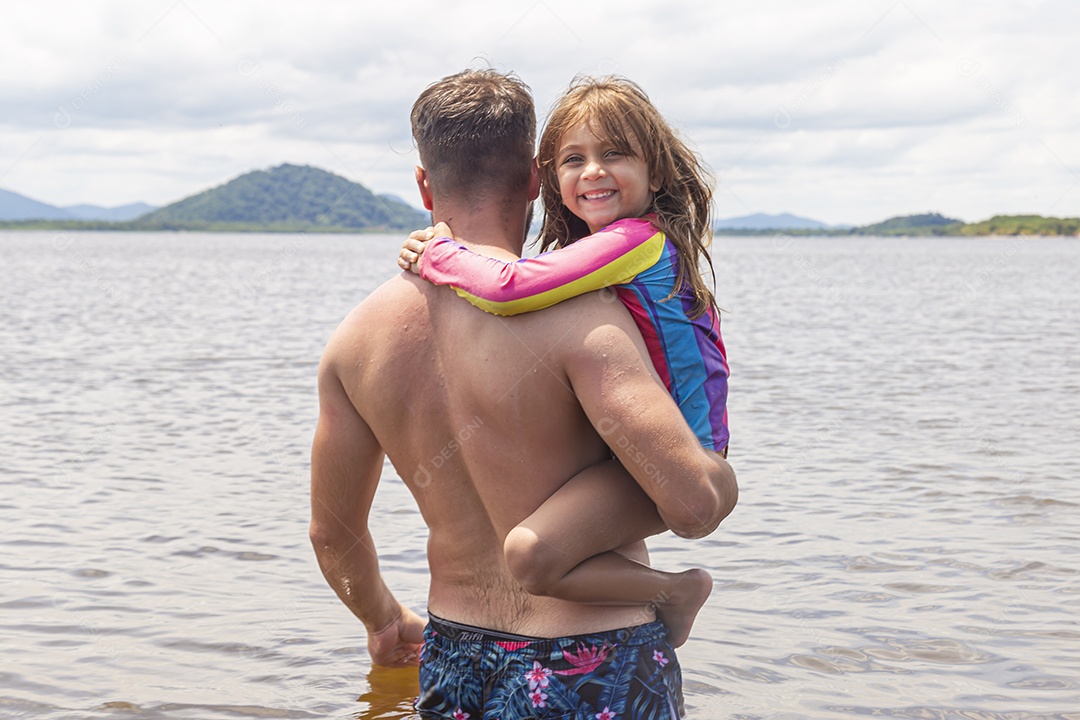 Pai ao lado de sua filha curtindo verão sobre uma praia