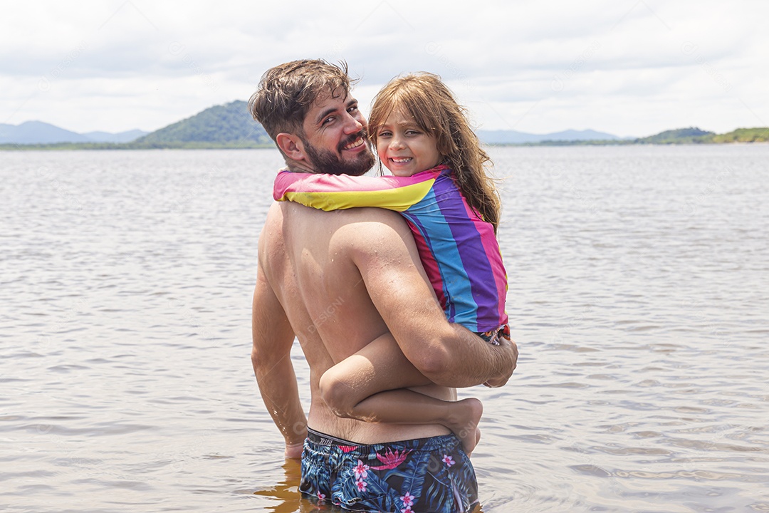 Pai ao lado de sua filha curtindo verão sobre uma praia