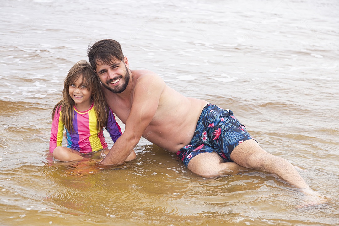 Pai ao lado de sua filha curtindo verão sobre uma praia