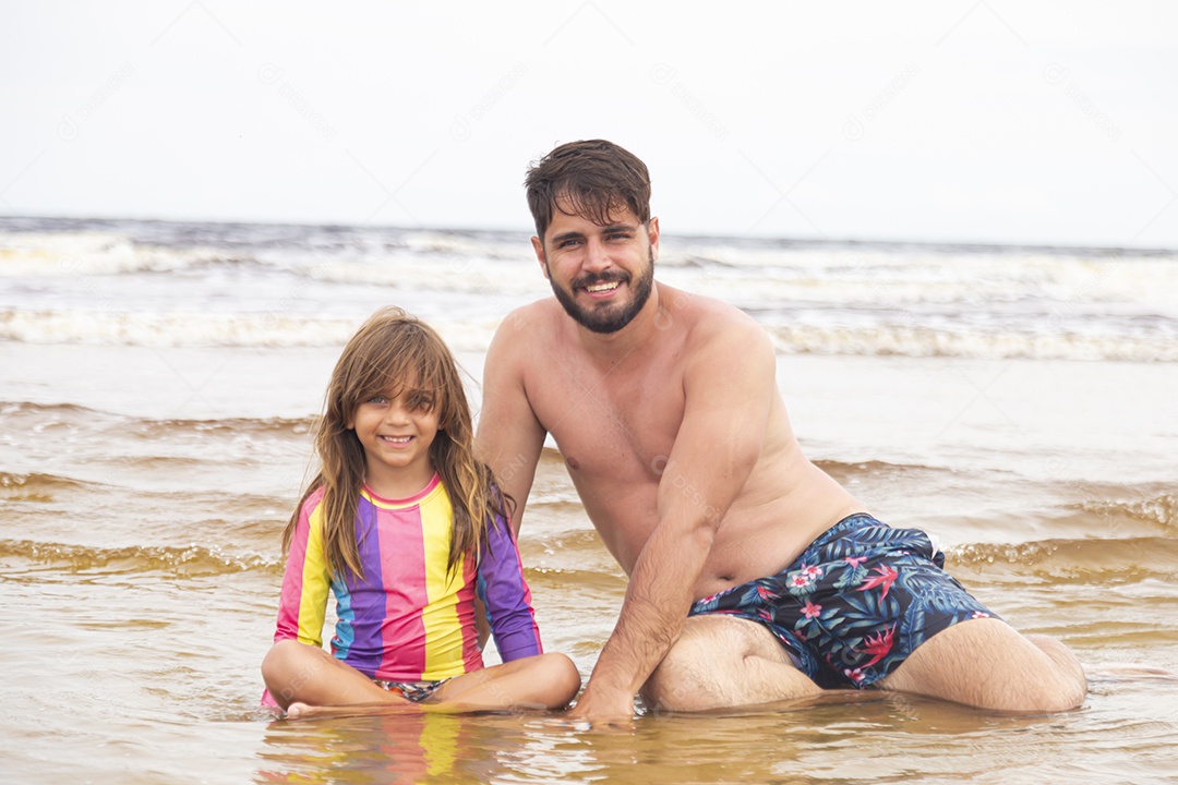 Pai ao lado de sua filha curtindo verão sobre uma praia