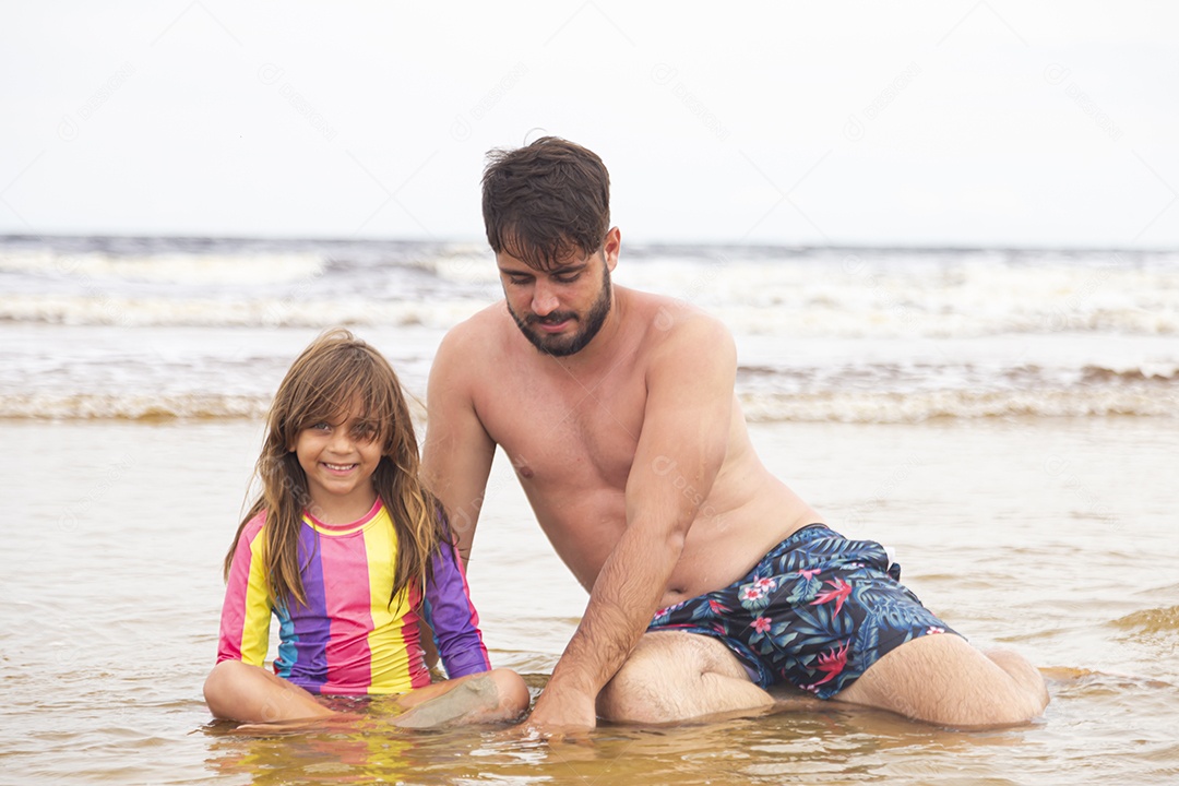 Pai ao lado de sua filha curtindo verão sobre uma praia