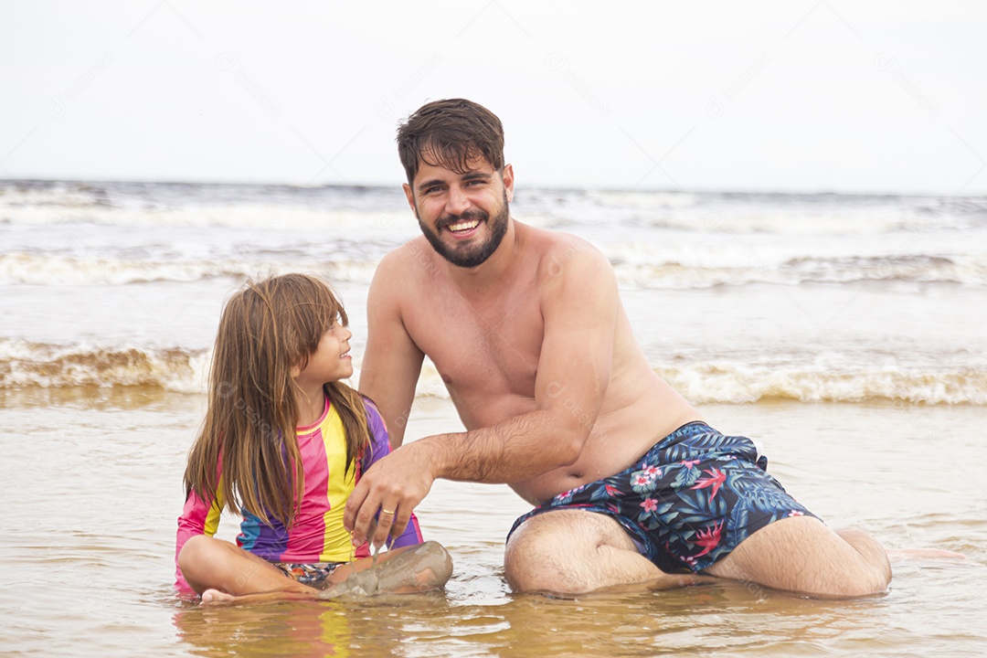 Pai ao lado de sua filha curtindo verão sobre uma praia