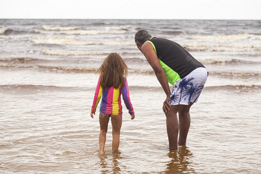 Pai ao lado de sua filha curtindo verão sobre uma praia
